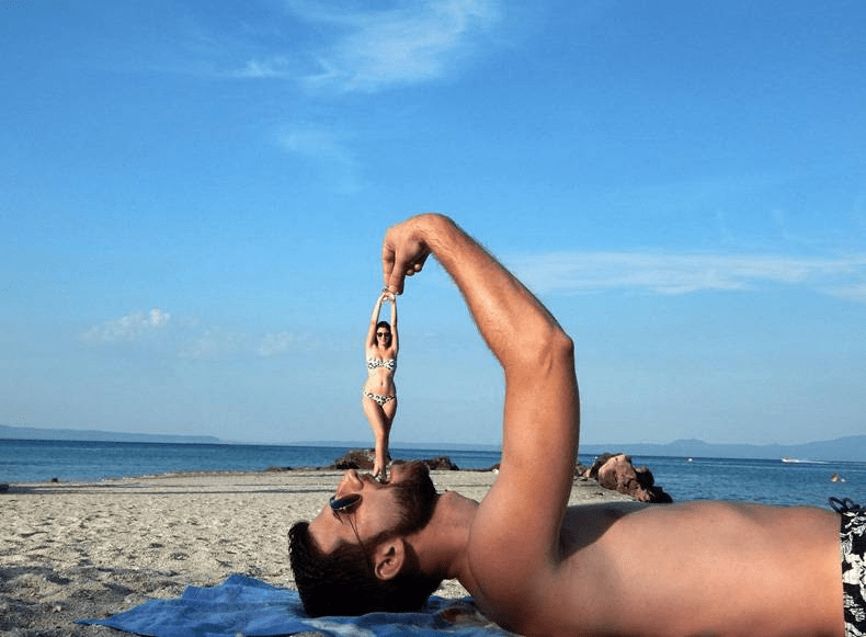 A person lying on the beach holding a fish
Description automatically generated with low confidence